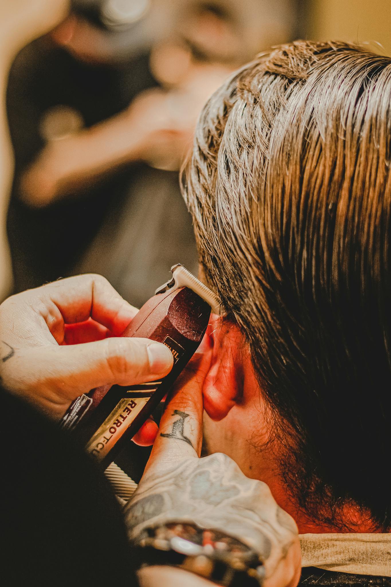 crop tattooed barber trimming hair of anonymous